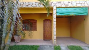 a yellow house with a door and a palm tree at Casa Temporada em Lumiar in Lumiar