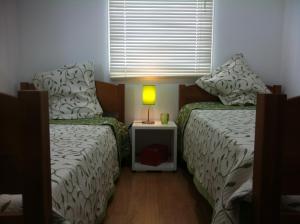1 dormitorio con 2 camas, lámpara y ventana en A Casa Da Avenida, en Madalena