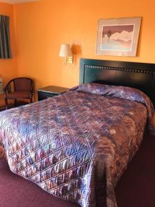 a hotel room with a bed and a chair at Pratt Budget Inn in Pratt