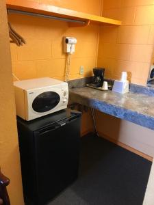 a microwave sitting on top of a refrigerator in a room at Pratt Budget Inn in Pratt