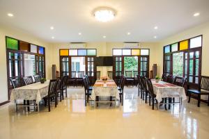 a dining room with tables and chairs and windows at Oh Amphawa Boutique Resort in Amphawa