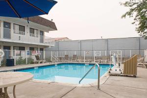 a swimming pool at a hotel with a table and an umbrella at Motel 6-Kalispell, MT in Kalispell