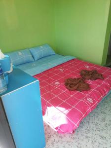 a bed in a room with a pink bedspread and brown clothes at Baan Oei Erng in Ban Laem Ngiu