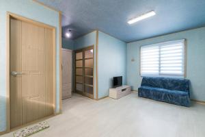 ein Wohnzimmer mit einem Sofa, einem Fenster und einer Tür in der Unterkunft Brassica Flower Pension in Seogwipo