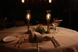 a table with a white table cloth with two candles and glasses at Vismaya by Moksha Stays in Turavūr