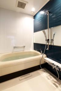 a bathroom with a bath tub and a sink at Gallery Nozawa Inn in Kyoto