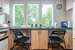 kuchnia z dwoma krzesłami przy blacie z dwoma oknami w obiekcie P&O Apartments Kasprzaka w Warszawie +8 zdjęć