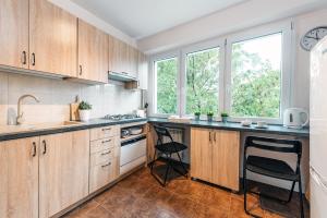 kuchnia z drewnianymi szafkami i blatem ze stołkami w obiekcie P&O Apartments Kasprzaka w Warszawie