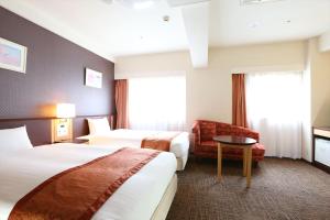 a hotel room with two beds and a chair at Hotel Hokke Club Fukuoka in Fukuoka