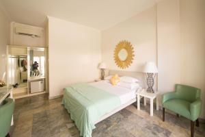 a bedroom with a bed and a chair and a mirror at Bali Court Hotel & Apartment in Legian +24 photos