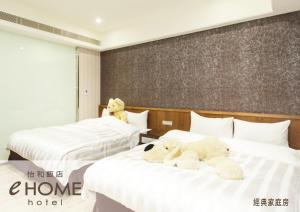 dos ositos de peluche sentados en dos camas en un hotel en eHome Hotel en Taoyuan