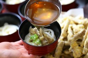 una persona está sosteniendo una taza de sopa con comida en Hotel Hokke Club Fukuoka, en Fukuoka