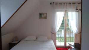 una camera con un letto bianco e una finestra di Les chambres du lac a Forges-les-Eaux