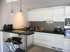 レイヨル・カナデル・シュル・メールにあるAppartement Duplex Proche Merのキッチン(白いキャビネット、黒いカウンタートップ付)