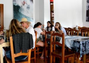 a group of people sitting around a table in a restaurant at Watsay Surf House in Santoña