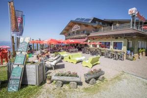 eine Außenterrasse mit Stühlen, Tischen und Sonnenschirmen in der Unterkunft Gasthof Kogelalm in Wagrain
