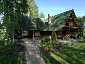 a house with a green roof and a patio at Guest House Vējaines in Vecslavēkas