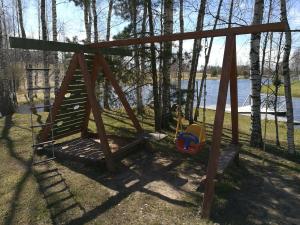 a swing set in a yard next to a lake at Guest House Vējaines in Vecslavēkas