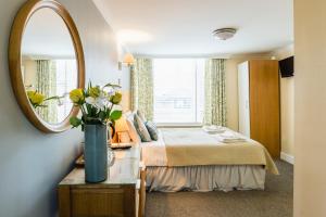 een hotelkamer met een bed en een spiegel bij George Oxford Hotel in Oxford
