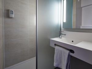 a bathroom with a sink, mirror, and towel rack at B&B Hotel Bordeaux Est in Tresses
