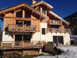 a large wooden house with a wrap around balcony at Chalet ChampBenoit in Valmorel