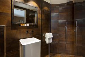 ein Bad mit einem Waschbecken und einer Dusche mit einem Spiegel in der Unterkunft Hotel Le Chat Noir in Paris