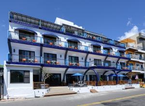 墾丁的住宿－墾丁海岸旅店，白色的建筑,设有蓝色的阳台,位于街道上