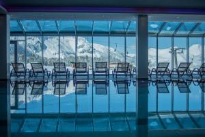 una piscina con sedie e vista sulle montagne di Hotel Almschlössl & Schrotteralm a Obertauern