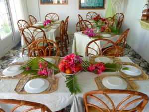 a dining room with two tables with white plates and flowers at Villa Kissen in Trou aux Biches