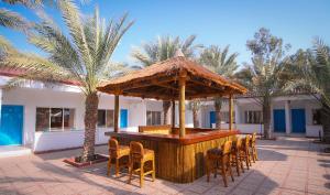 a bar in a resort with chairs and palm trees at Fujairah Hotel & Resort in Fujairah
