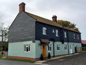 Lawson Cottage B&B في Hickling: منزل أبيض وأزرق بسقف أسود