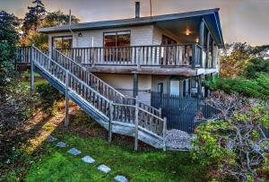 een huis met een groot terras en een veranda bij Cove Beach Apartment 2 in Coles Bay