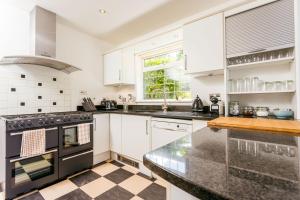 a kitchen with white cabinets and black appliances at The Queen Edith Place - Lovely 6BDR Home in Secluded Area in Cambridge