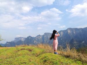 een vrouw die op een heuvel staat en naar de bergen kijkt bij Zhangjiajie Jijiehao Inn in Zhangjiajie