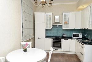 a kitchen with white cabinets and a white table at Apartment on Bulvar Mira 8 in Karagandy