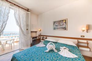 Una habitación de hotel con una cama con dos vestidos. en Hotel Villa Laura en Rímini