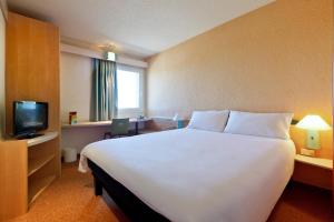 una camera d'albergo con un grande letto e una TV di Hotel ibis Porto Sul Europarque a Santa Maria Da Feira