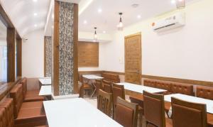 una sala da pranzo con tavoli e sedie bianchi di Treebo Trend Amber International a Mumbai