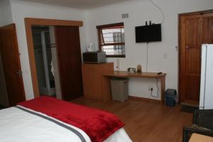 a bedroom with a bed and a desk and a television at 34 On Marten Crescent in Table View