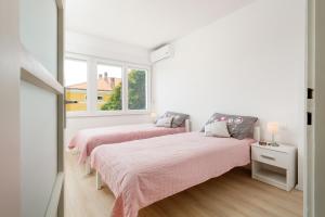 twee bedden in een witte kamer met twee ramen bij Botun Apartman free parking in Pula
