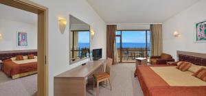 a hotel room with two beds a desk and a television at SOL by Meliá Nessebar Palace All Inclusive in Nesebar