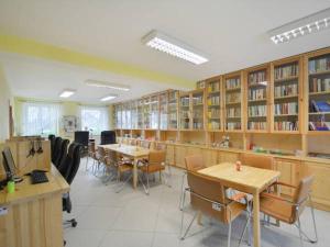 eine Bibliothek mit Tischen, Stühlen und Bücherregalen in der Unterkunft Bumerang in Nowa Biała