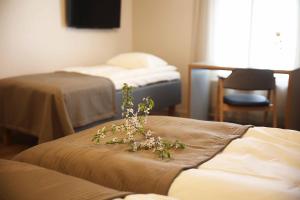 a room with two beds and a table with flowers on it at Savonlinnan Kansanopisto - Wanha Pappila in Savonlinna