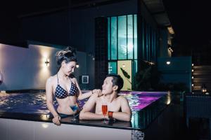 Un uomo e una donna seduti in piscina di The Xtreme Suites a Bangkok