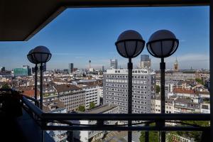 a view of a city from a window with three lights at Clayton Hotel Düsseldorf City Centre in Düsseldorf