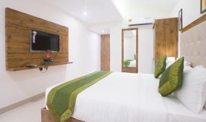 a bedroom with a white bed with a tv on the wall at Treebo Trend Amber International in Mumbai