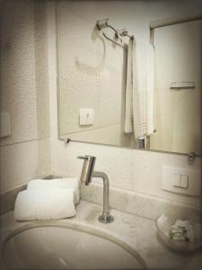uma casa de banho com lavatório, espelho e toalhas em Pousada Rancho do Ralf em Pirenópolis