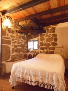 1 dormitorio con 1 cama en una pared de piedra en Casa do Forno en Valezim