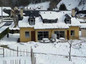 Una casa amarilla con nieve encima. en Gite La Balaguere, en Cauterets