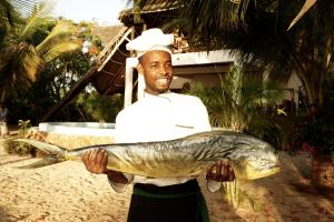 um homem segurando um peixe em suas mãos em Milele Villas em Potoa